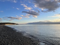 a beach with water and clouds in the background